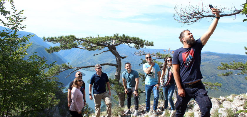 Group of travelers taking selfie with Drina river in the back
