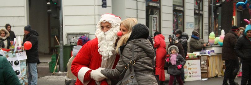 Santa Claus and a girl with red nose are posing on the street of open heart in Belgrade. 