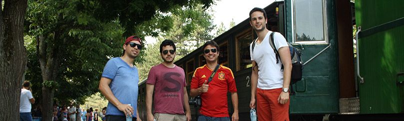 Group of four friends is standing beside the Sargan eight train on Mokra gora in Serbia