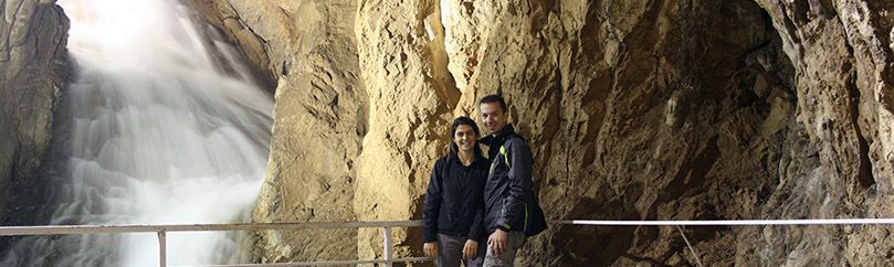 Married couple is posing beside the waterfall in Stopica cave on Zlatibor in Serbia