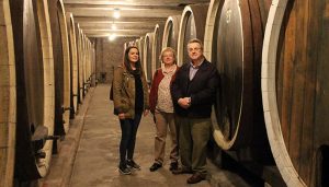 Three people are posing in King’s cellar and learning about wines of Sumadija.